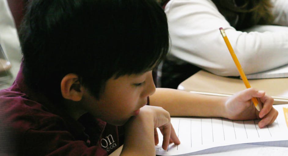 Child writing with a pencil in a notebook