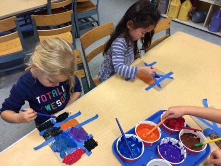Two children painting at a table in a classroom