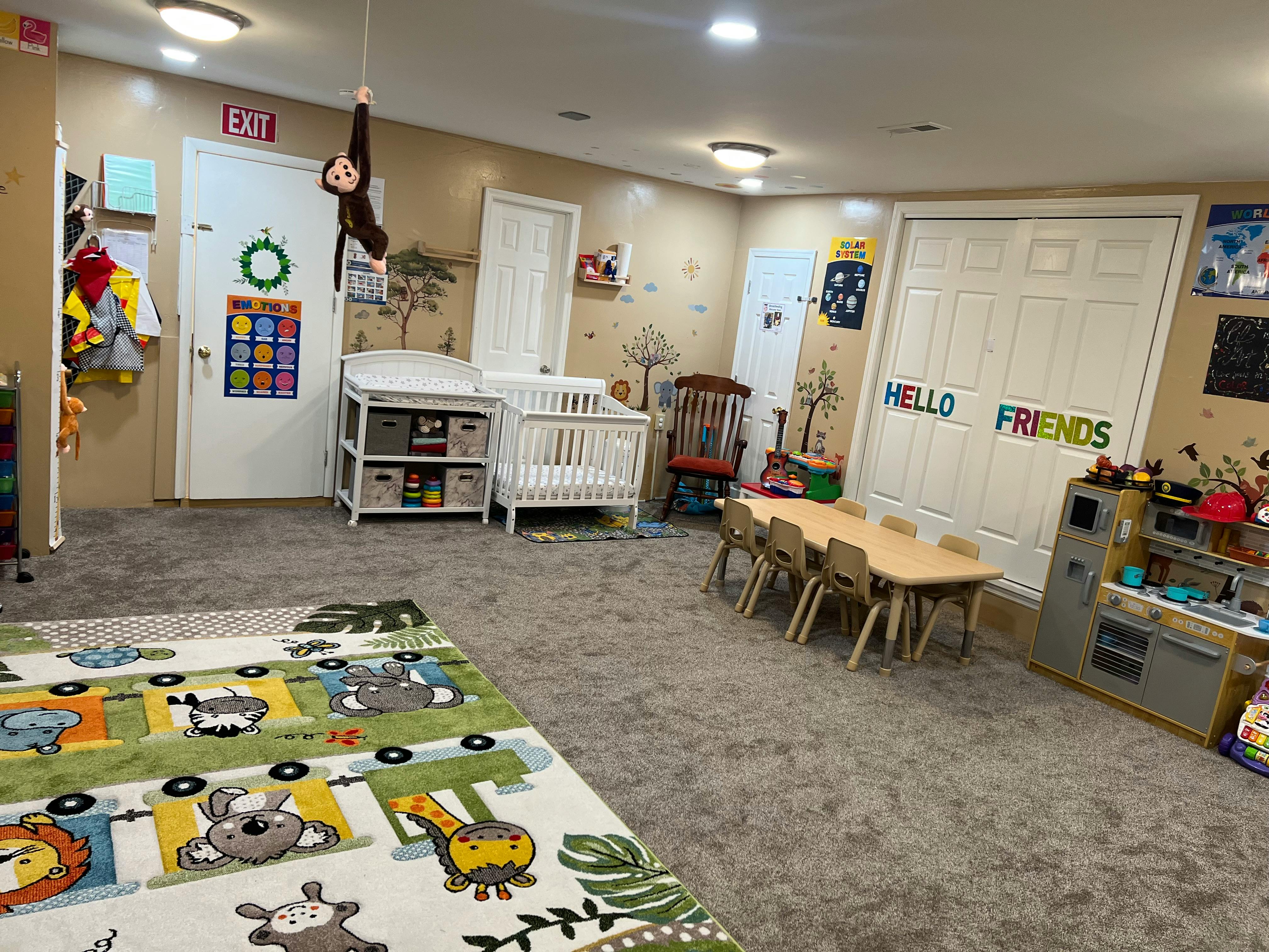 Daycare room with crib, changing table, small table and chairs, and play kitchen