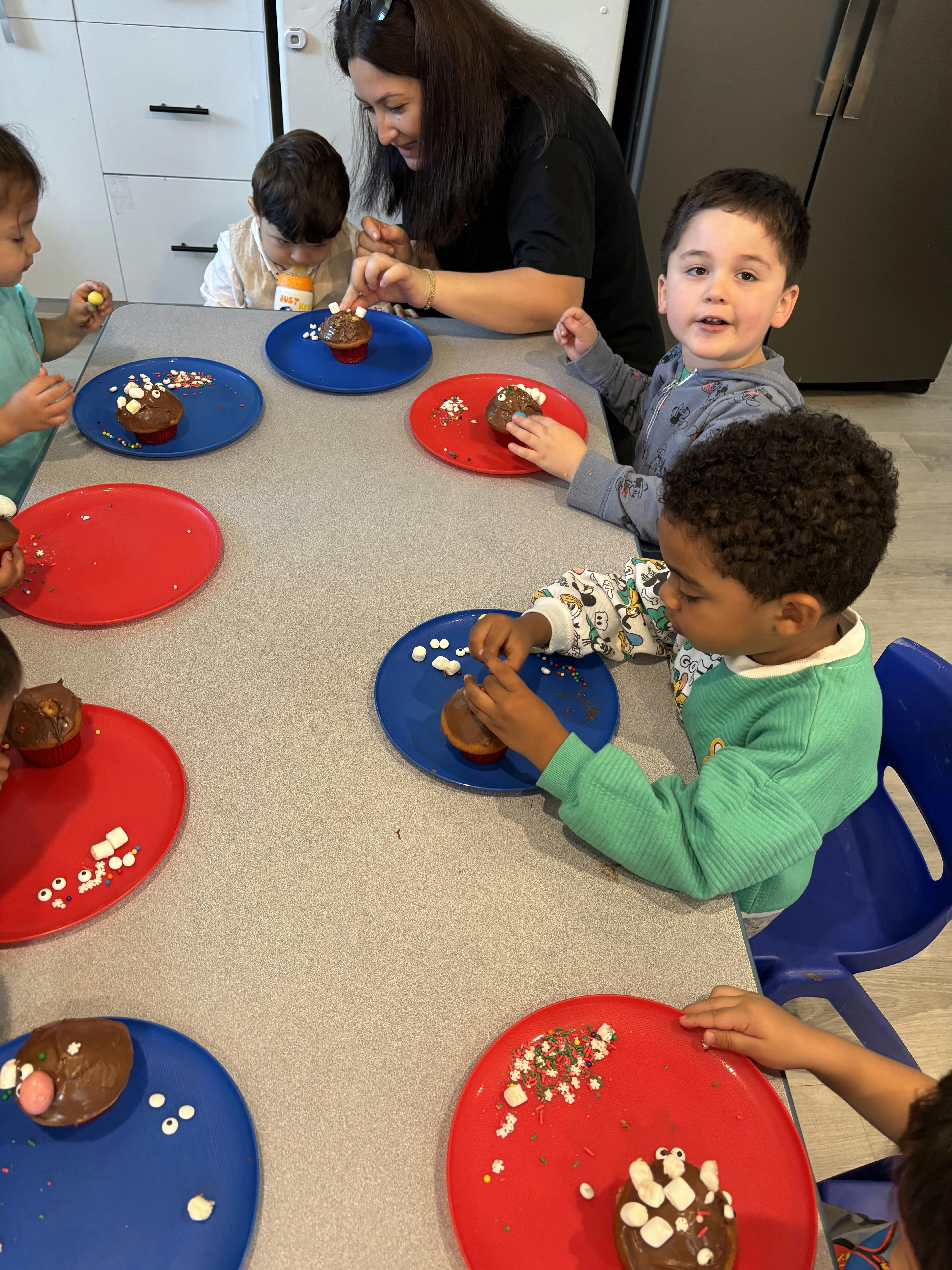 Adult and children decorating cupcakes at a table