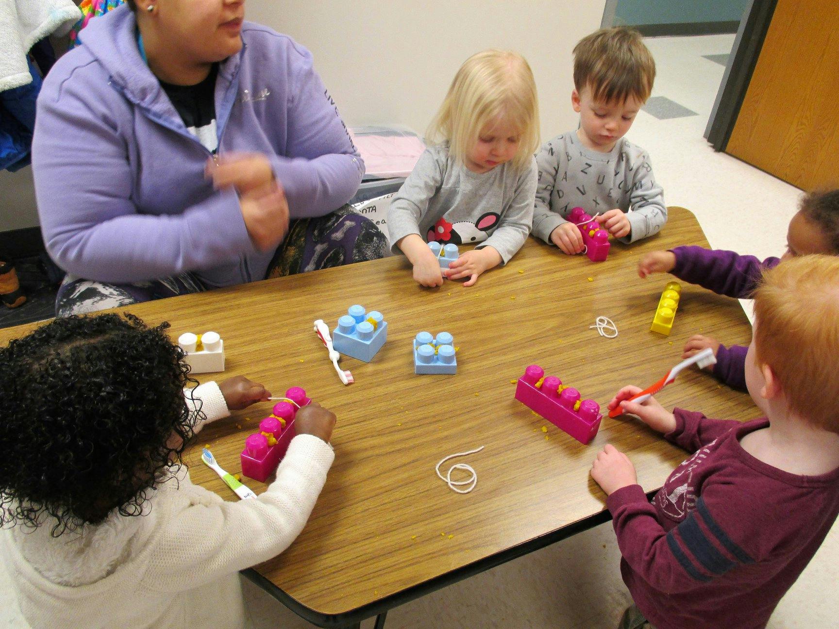 Person and children playing with building blocks at a table