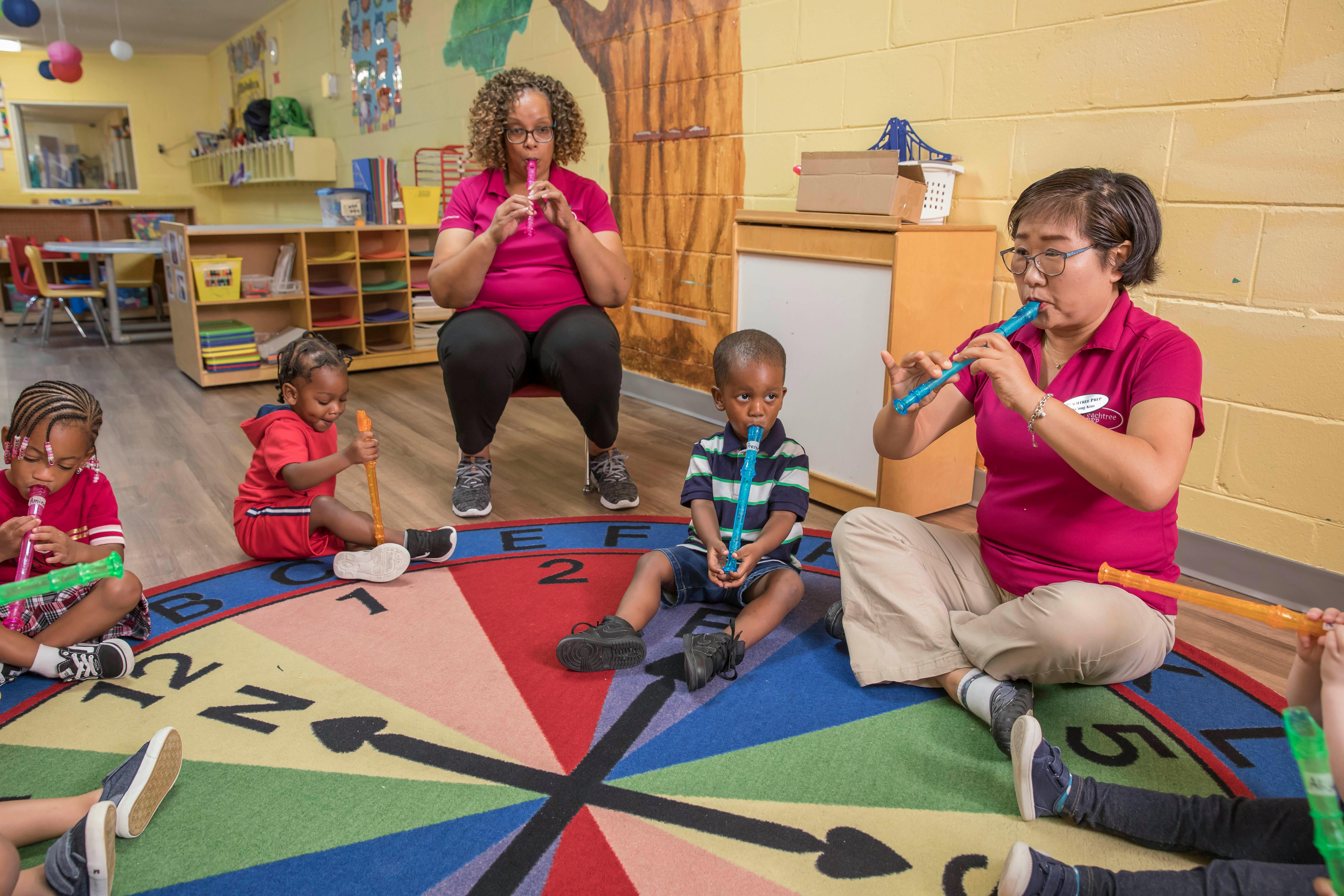 Adults and children playing flutes in a classroom