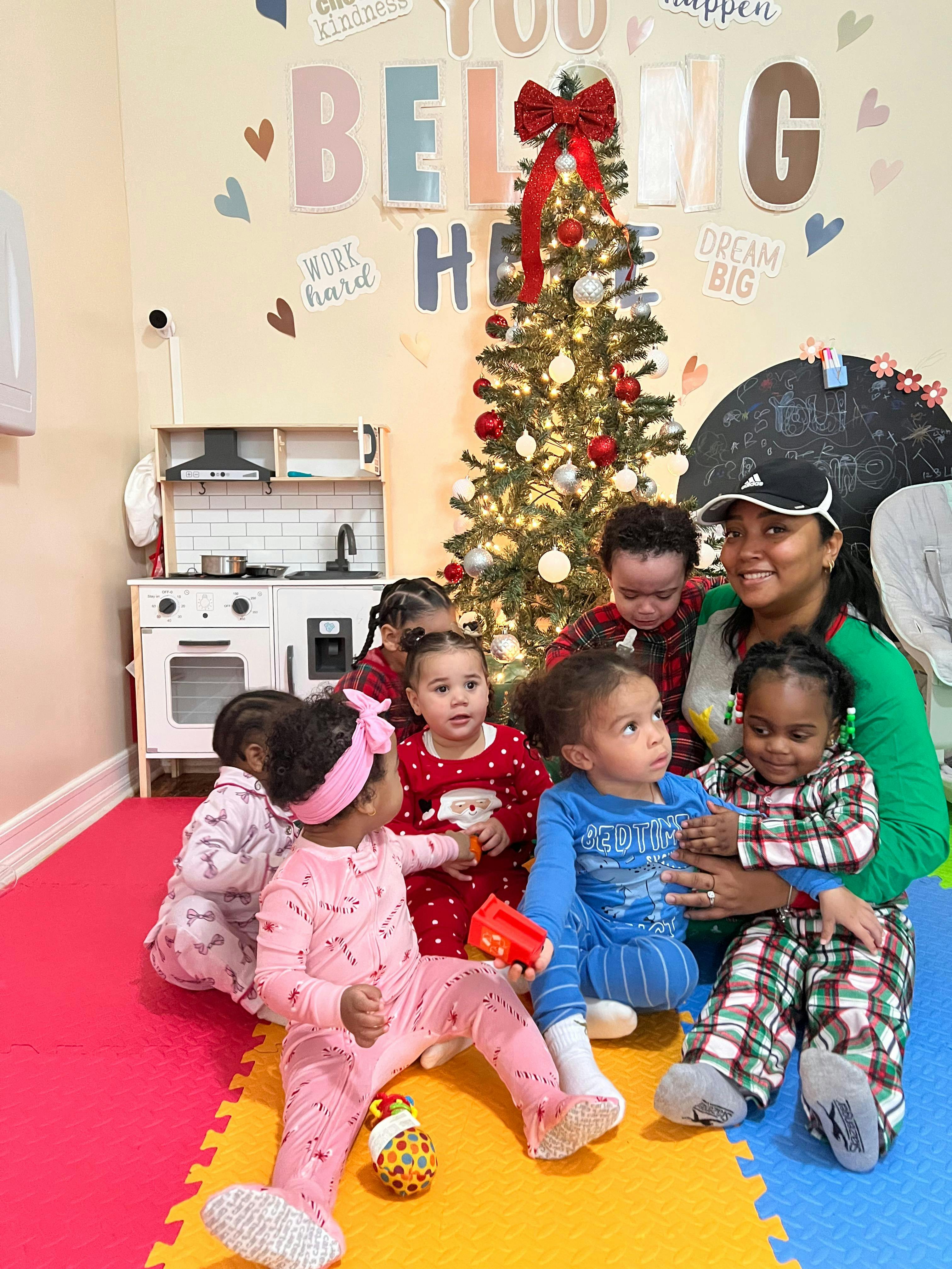 Adult and multiple children sitting on the floor in front of a Christmas tree