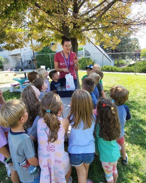 Adult person speaking to a group of children outdoors