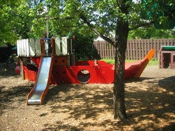 Red playground structure shaped like a ship with a slide