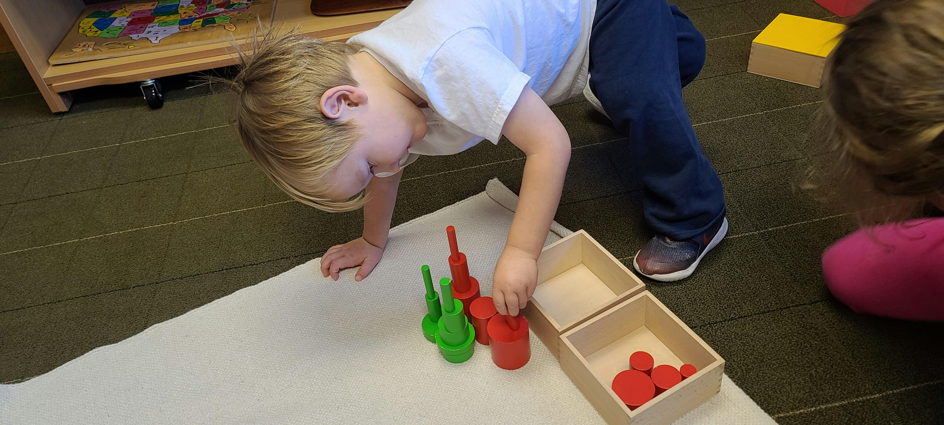 Child playing with red and green plastic shapes on a mat