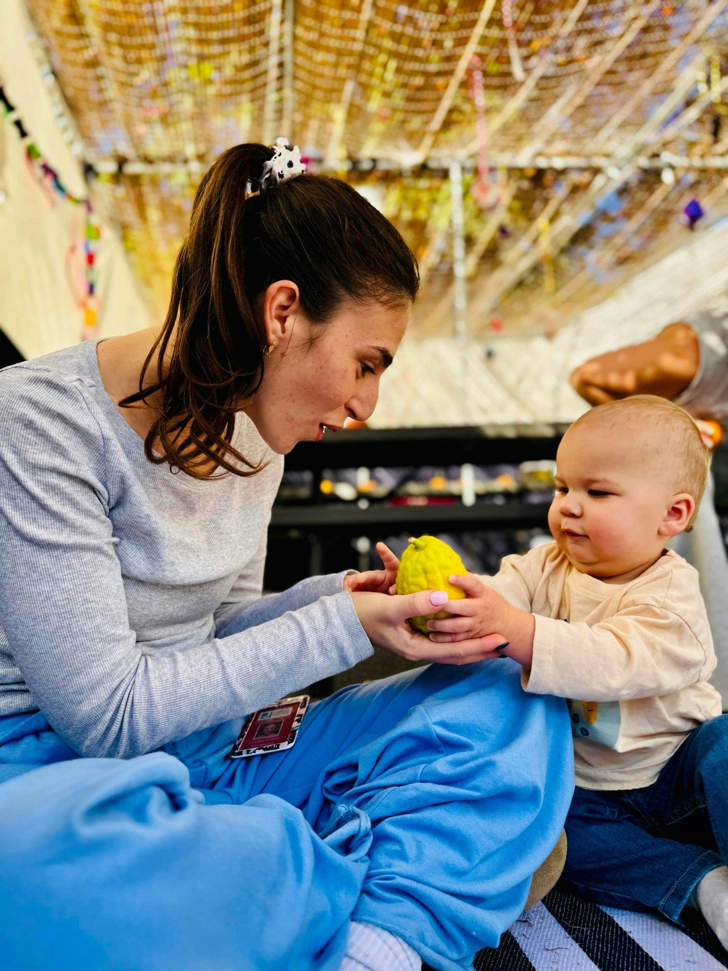 A person holding a yellow citron fruit with a child