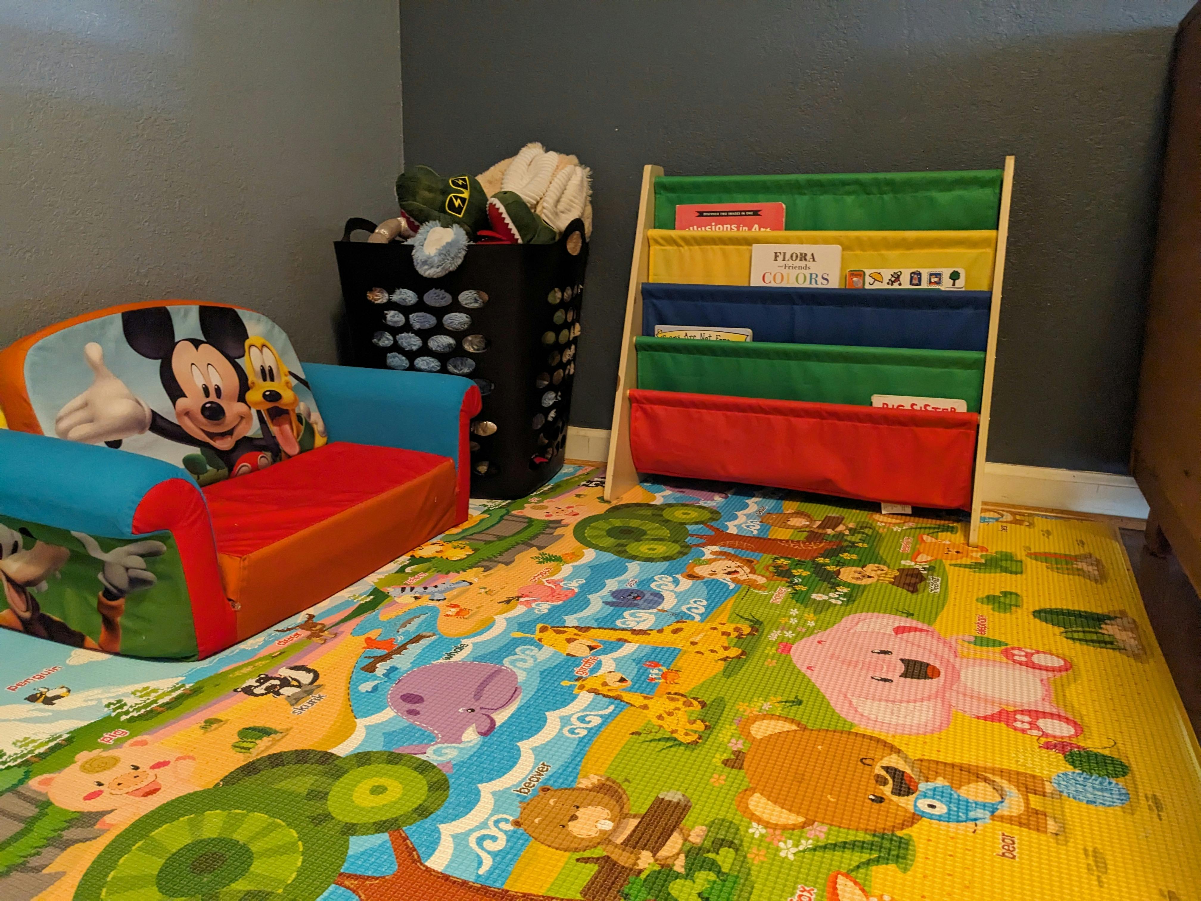 Child's room with a Mickey Mouse chair, laundry basket, and book display