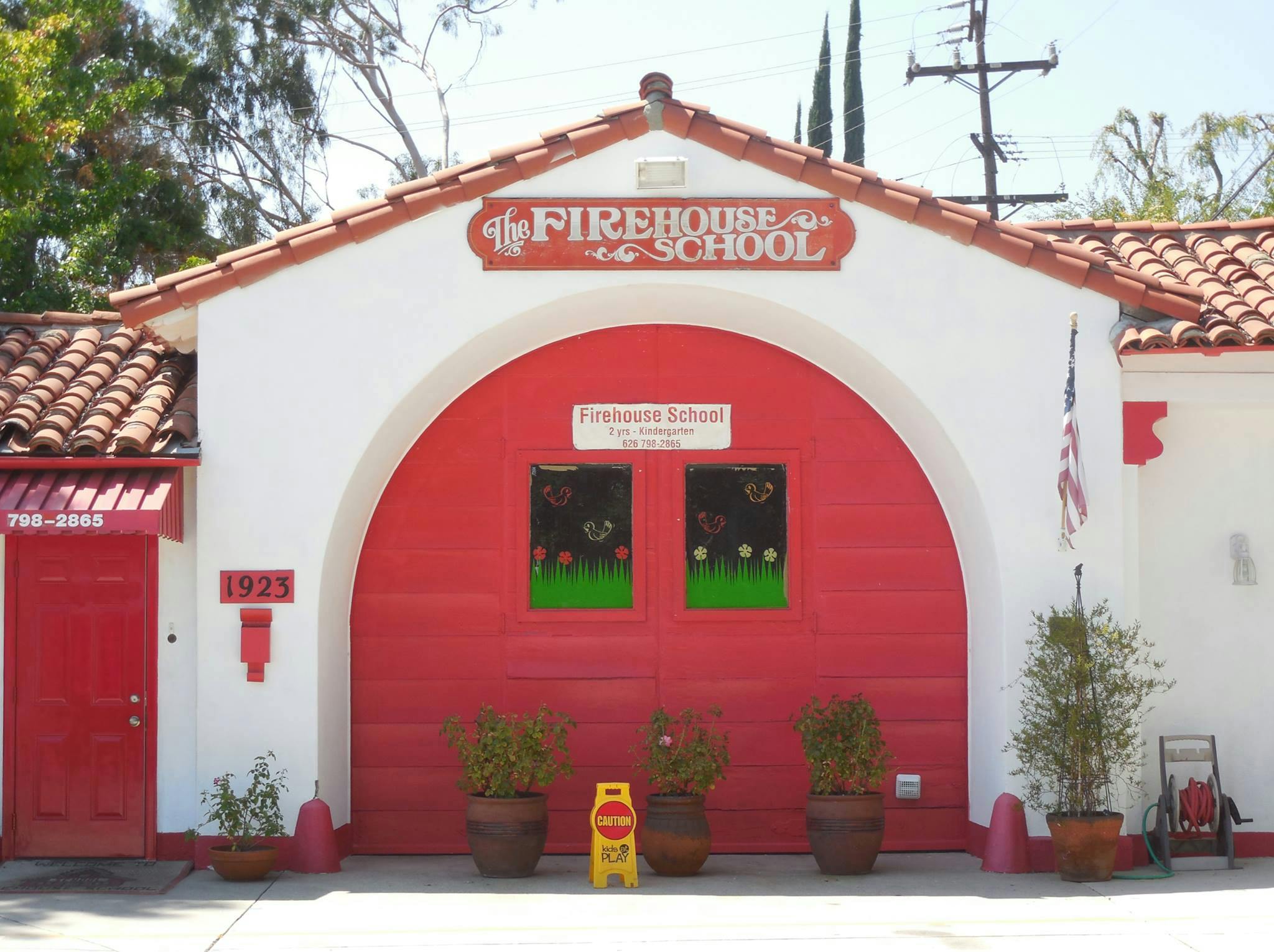 Building with red arched garage door and sign "The Firehouse School"