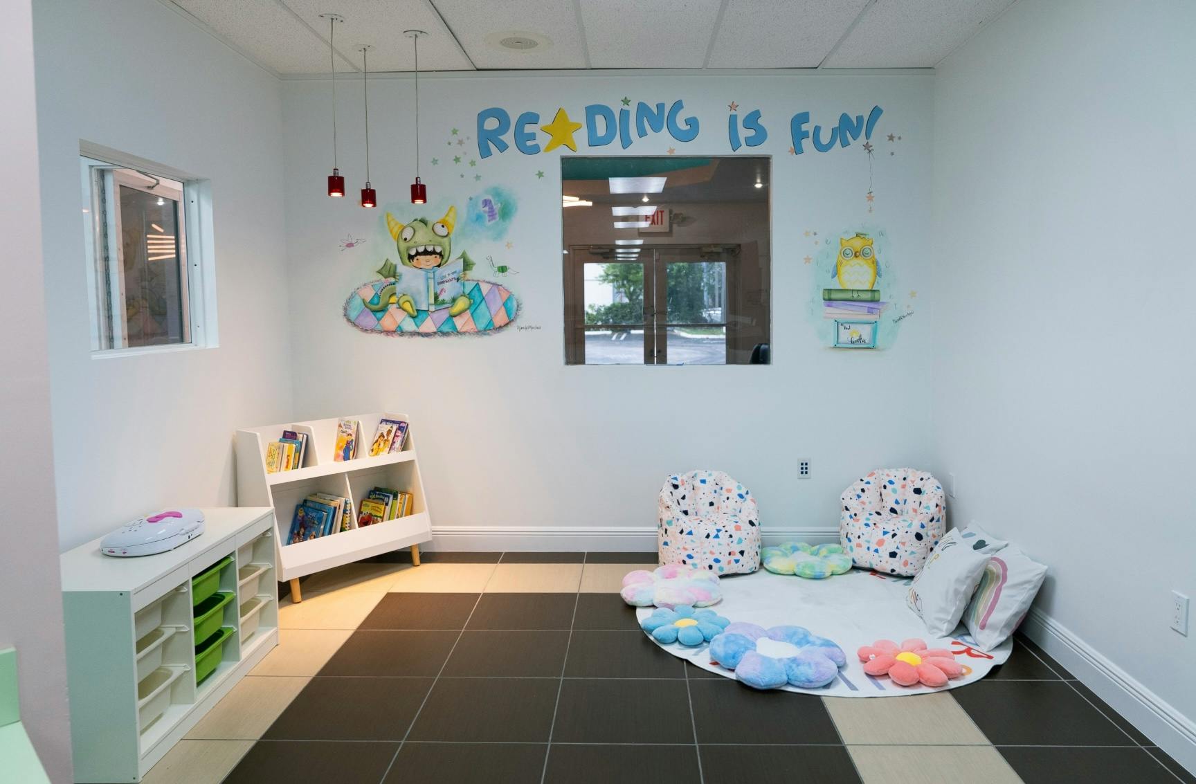 Reading nook with floor cushions and a bookshelf, "Reading is Fun!" on wall