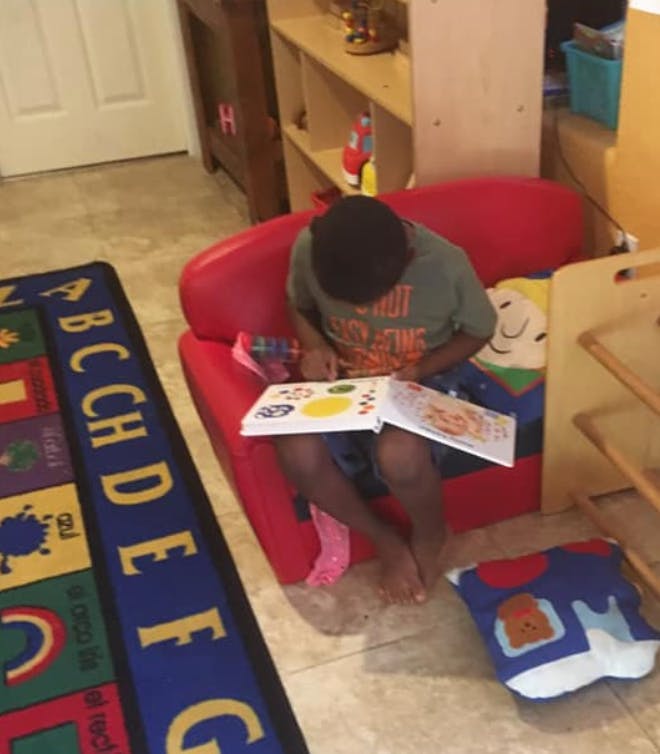 Child sitting on a red chair reading a book