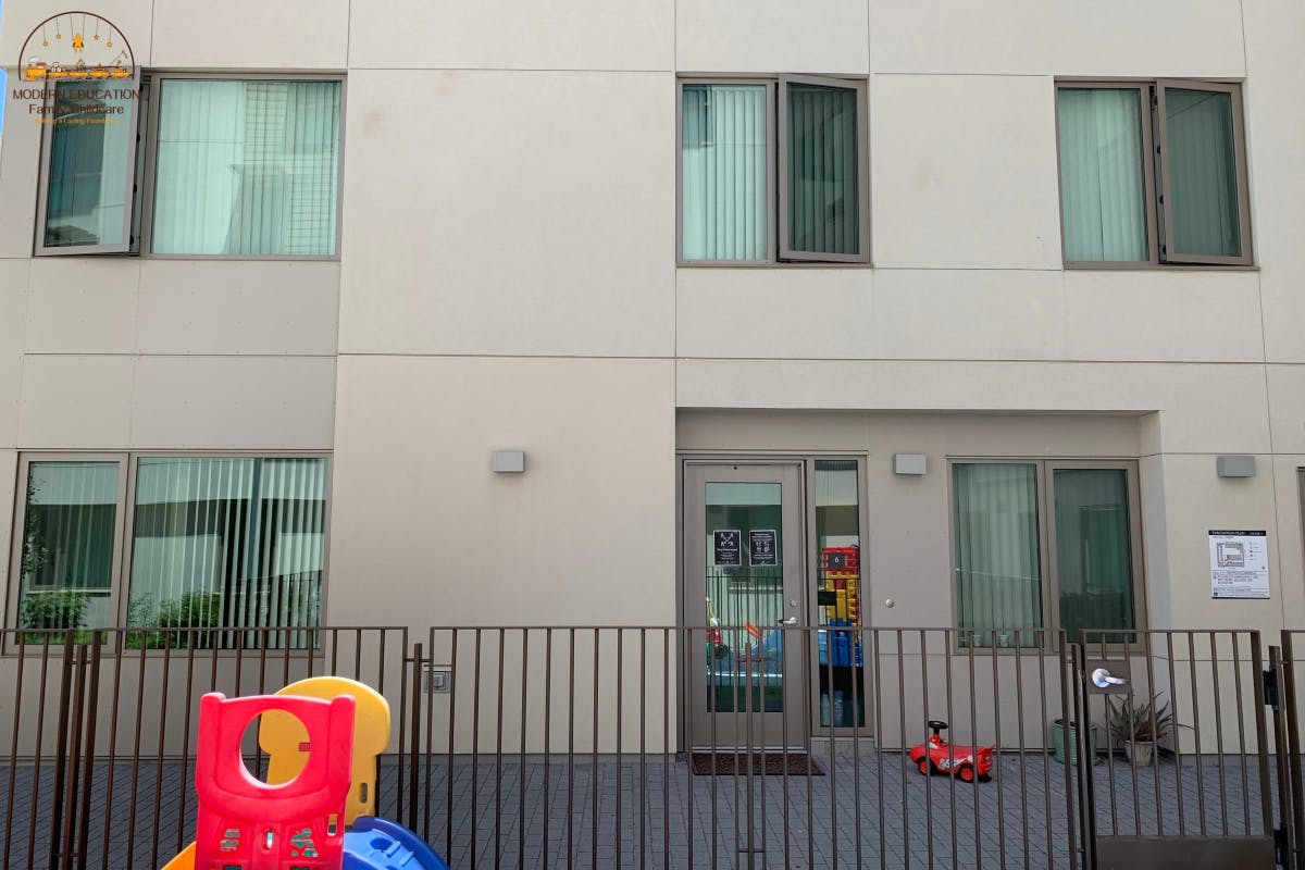 Building exterior with windows, a glass door, and a fence in front