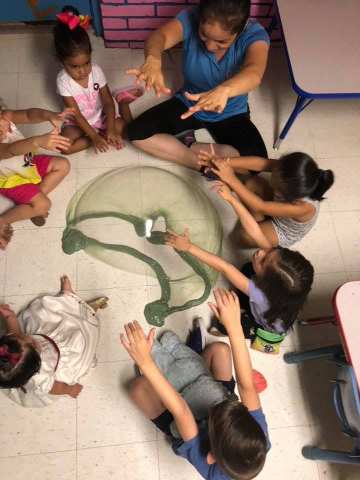 Adult and children sitting on floor playing with green slime
