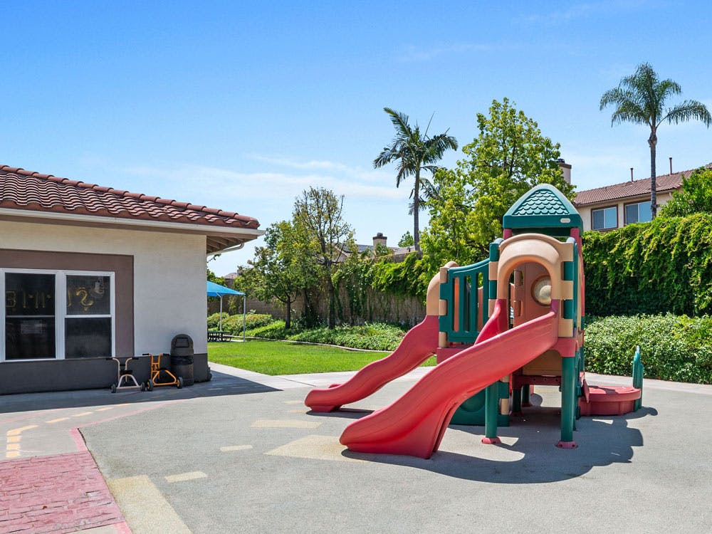 Playground with a slide and climbing structure next to a building