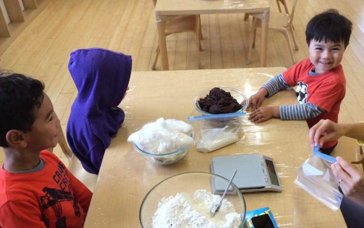Two children at a table with bowls of ingredients