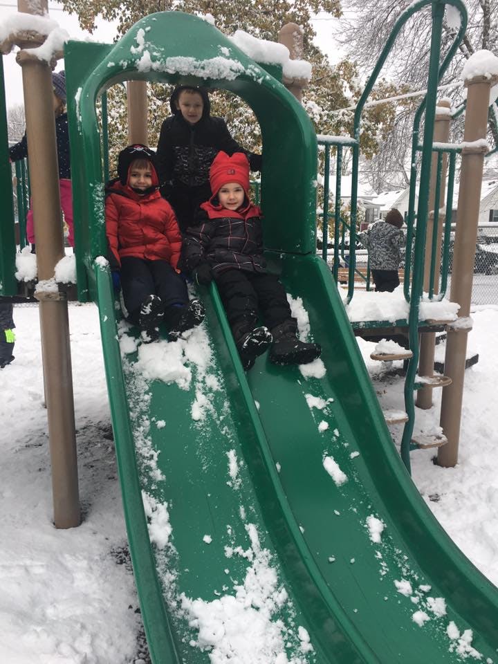 Three children on a snowy playground slide