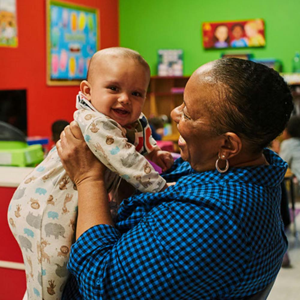 Person holding a smiling infant in a colorful room