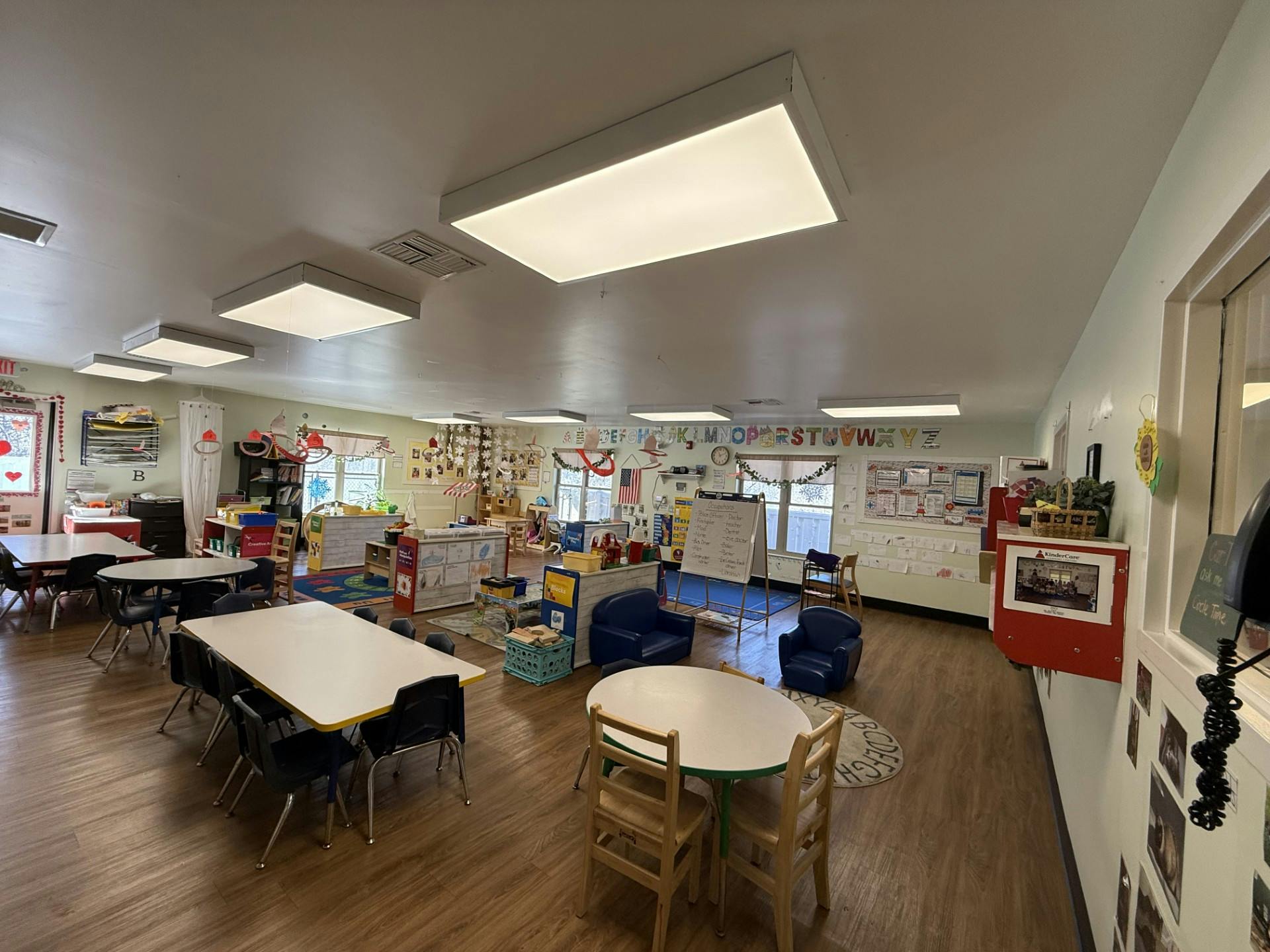 Classroom with child-sized tables and chairs, play areas, and alphabet decorations