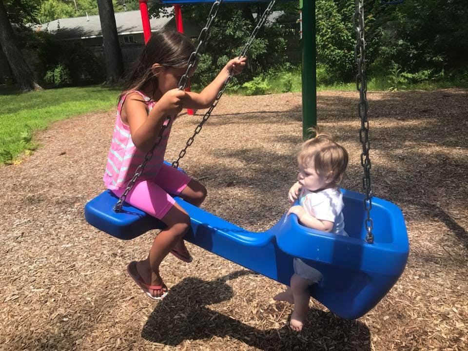 Child and toddler on a blue swing set