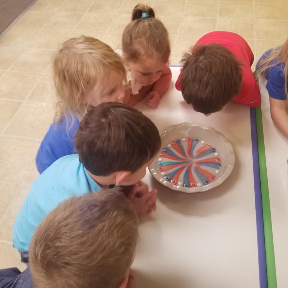 Children looking at a bowl with a colorful pattern