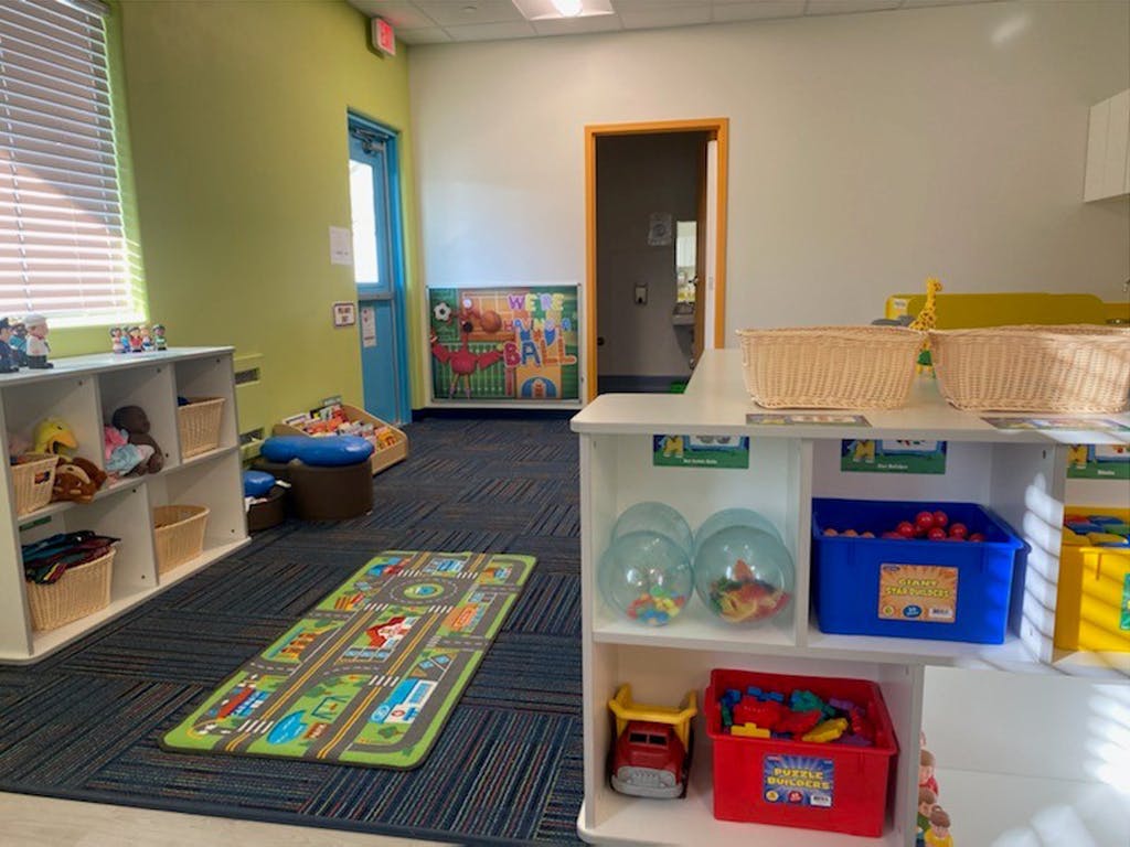 Playroom with shelves of toys and a road map rug on the floor