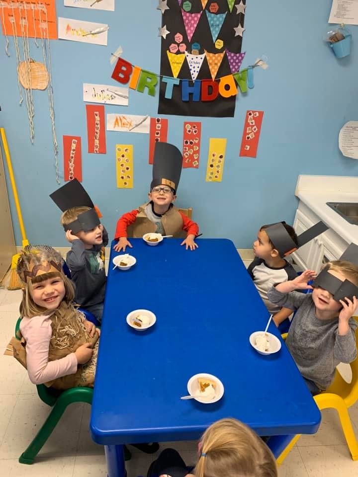Children in costumes sitting at a table with bowls of food