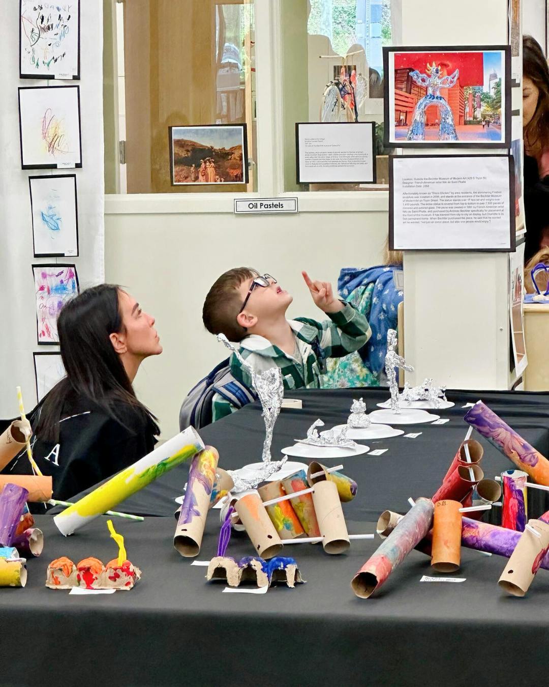 People viewing art displays, one person pointing up