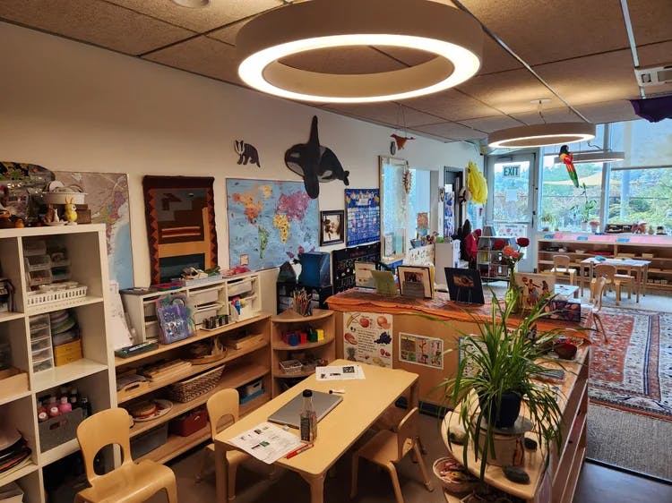 Classroom with children's tables and chairs, shelves, and colorful wall decorations