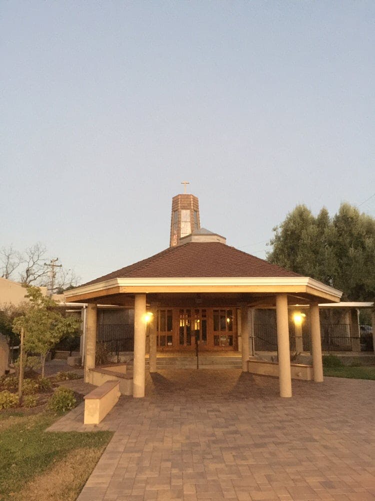 Building with a brown roof and a small tower with a cross on top