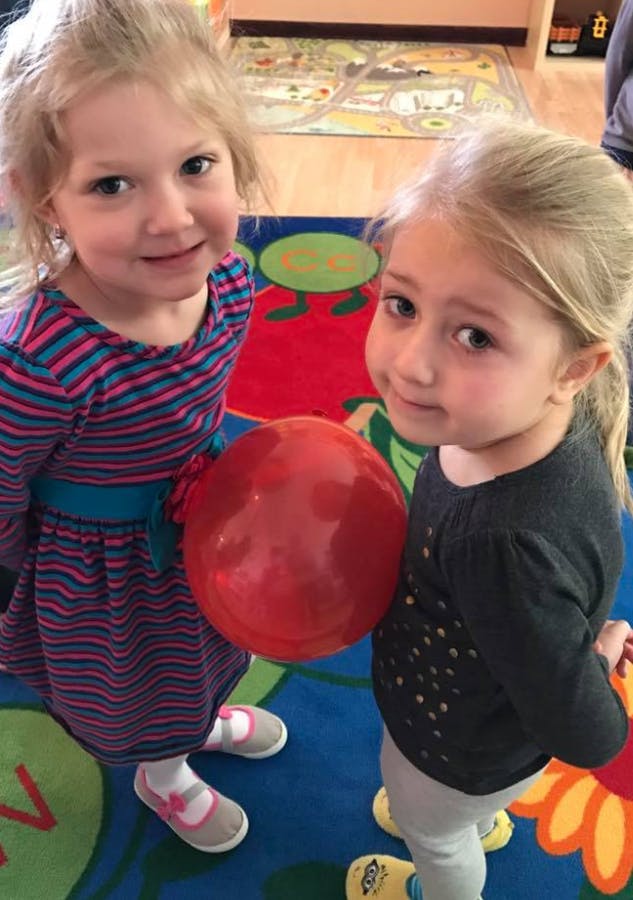 Two children standing with a red ball