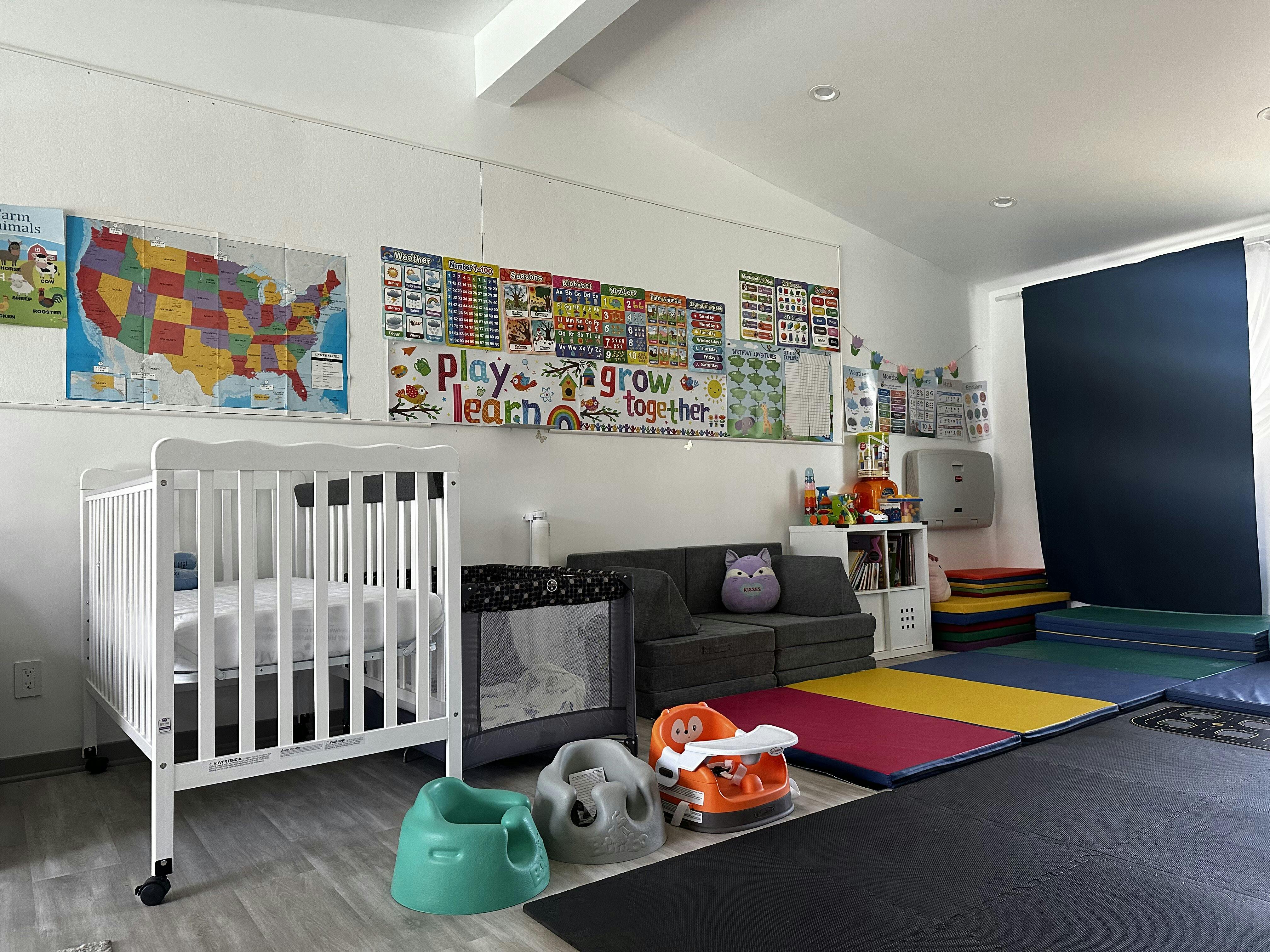 Nursery room with a crib, playpen, couch, and colorful mats