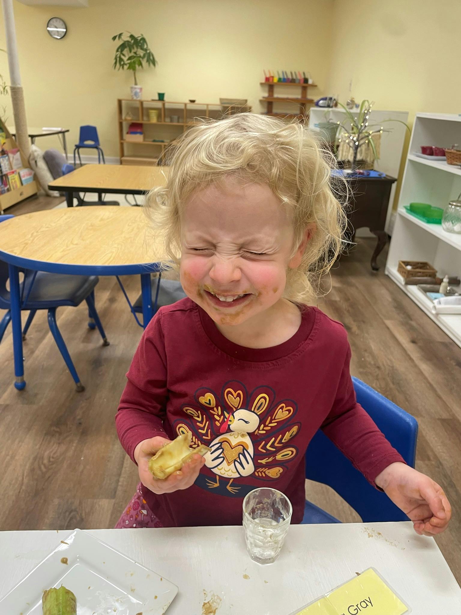 Child with food on face holding food in a classroom