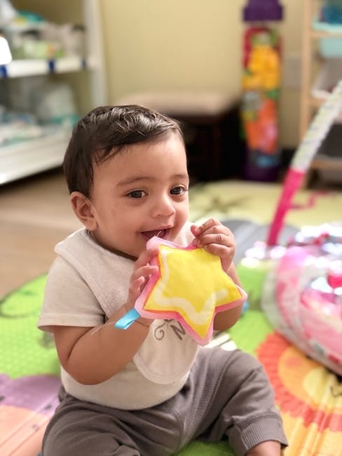 Child sitting on a play mat holding a fabric star toy