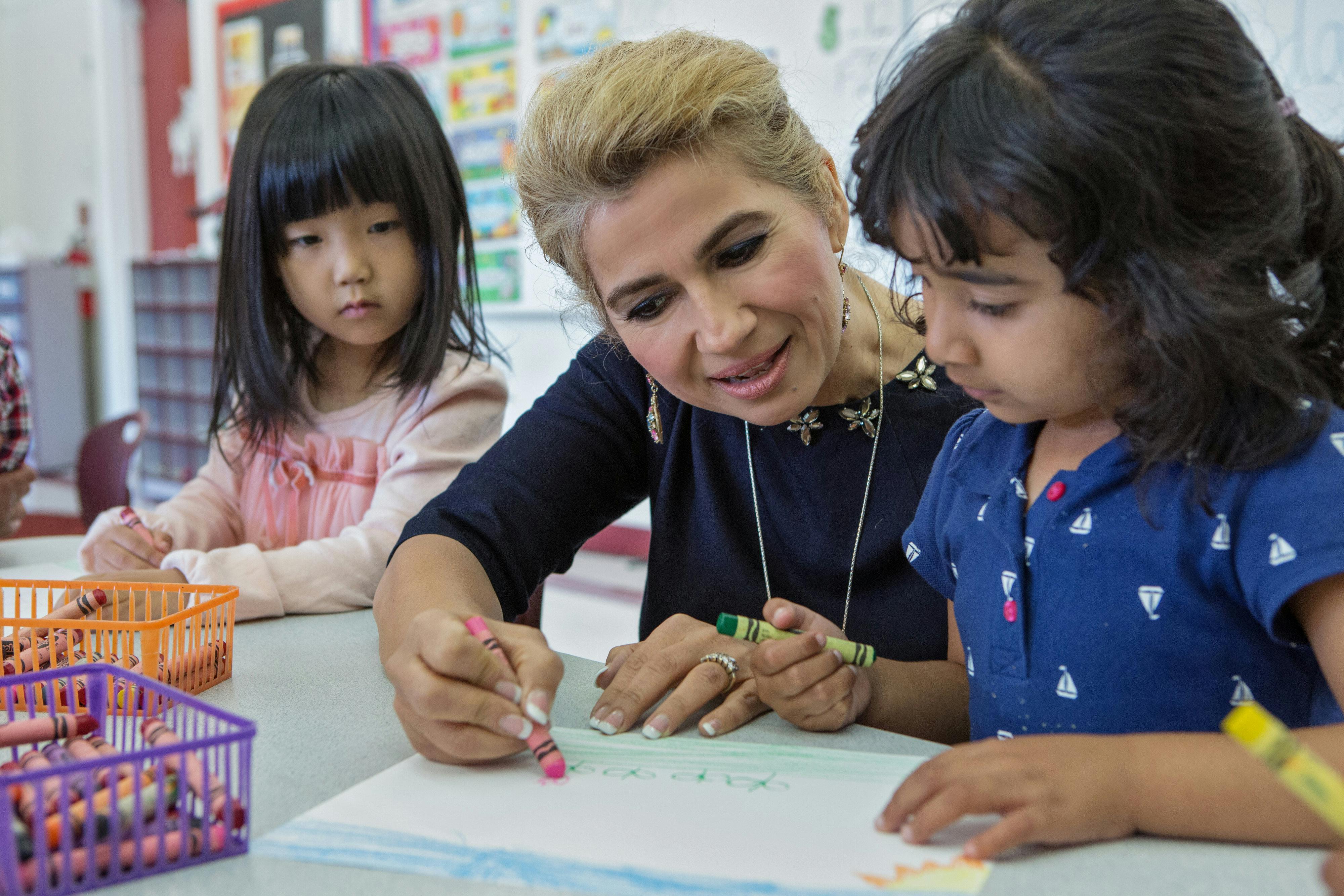 Adult and two children drawing with crayons at a table
