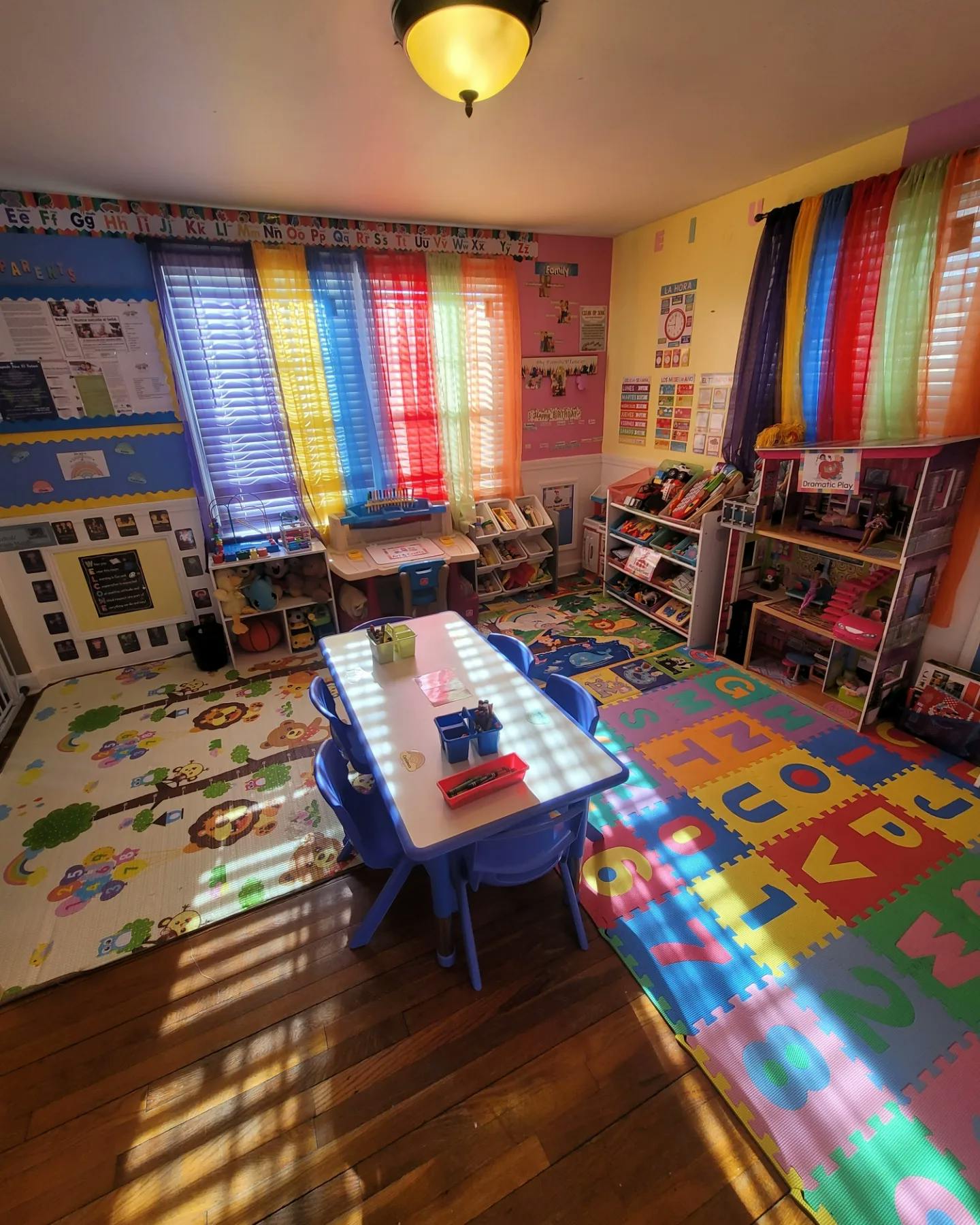 Classroom with colorful blinds, play mats, and a table with chairs
