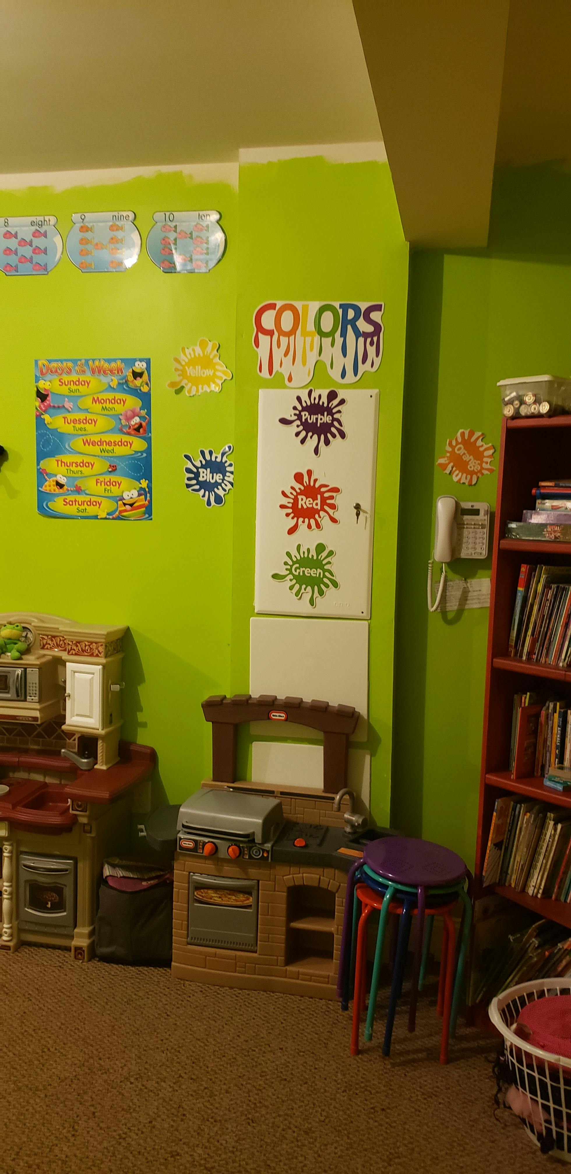 Play kitchen and grill set in a room with lime green walls and educational posters