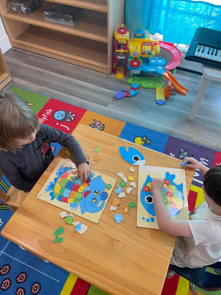 Two children playing with puzzles at a table