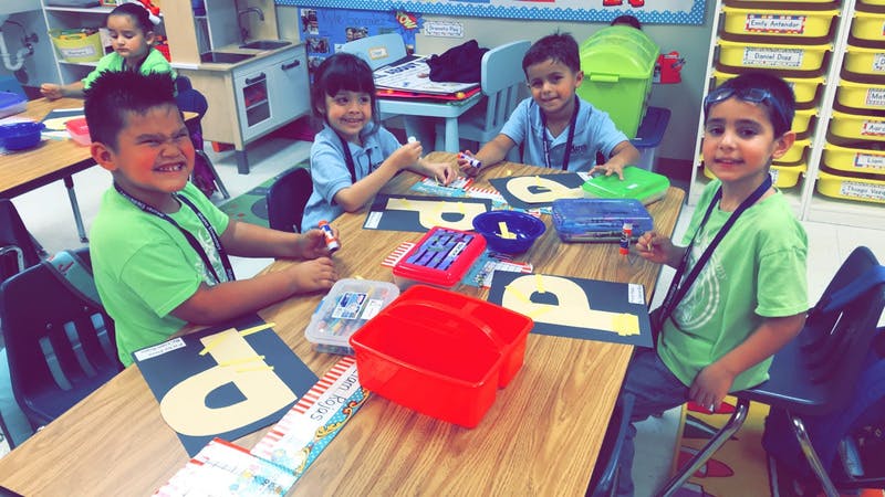 Children at a table with craft supplies and letter cutouts