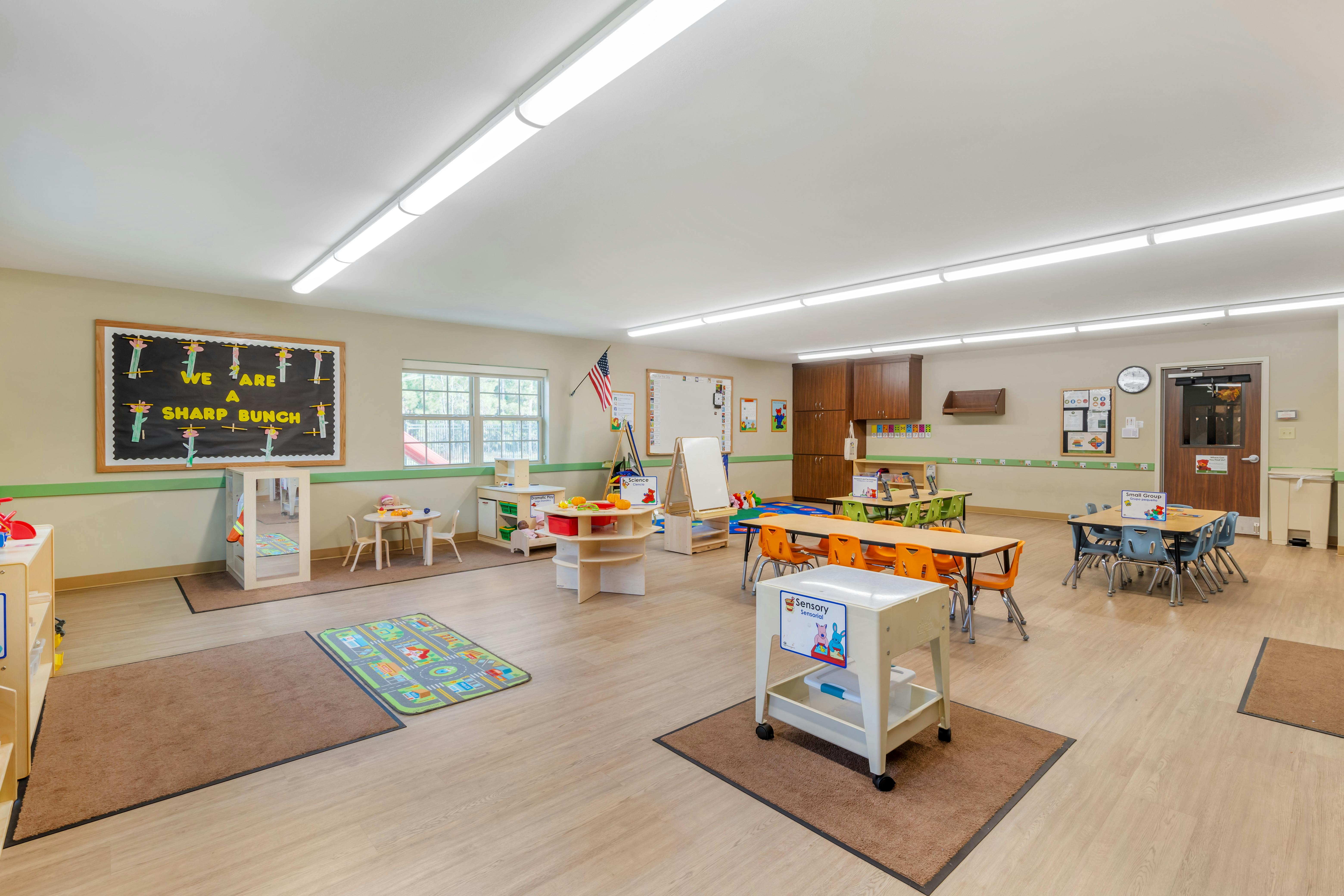 Classroom with multiple activity stations, tables with chairs, and a window