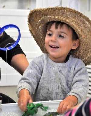 Child in a straw hat playing with toys in water