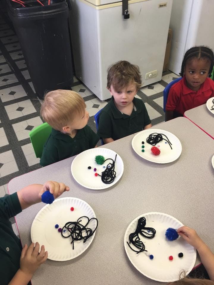 Children at a table with plates of craft supplies