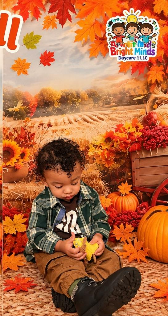 Child sitting on floor in a fall-themed setting with pumpkins and leaves