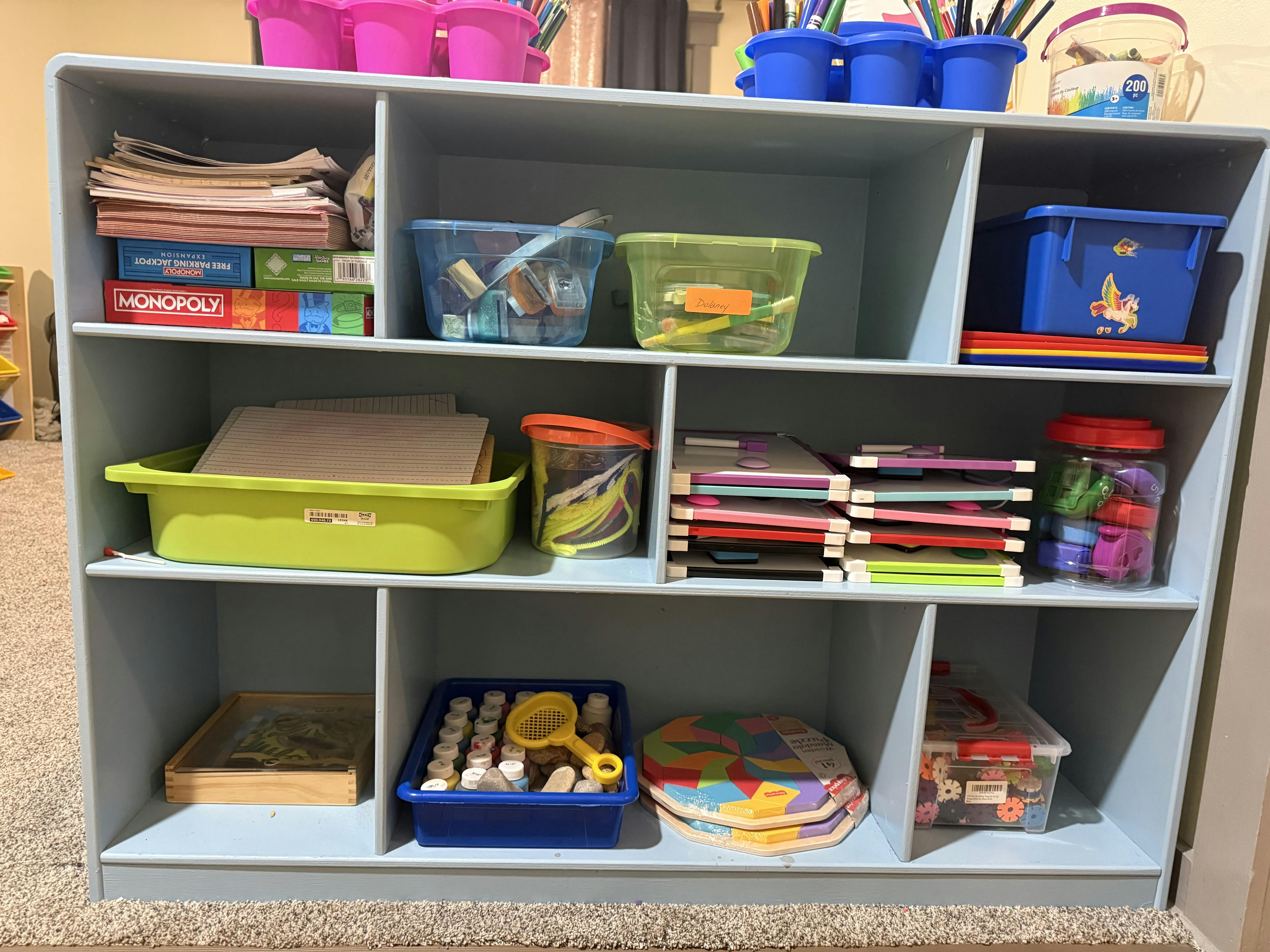 Cubby shelf unit filled with crafts, games, and school supplies