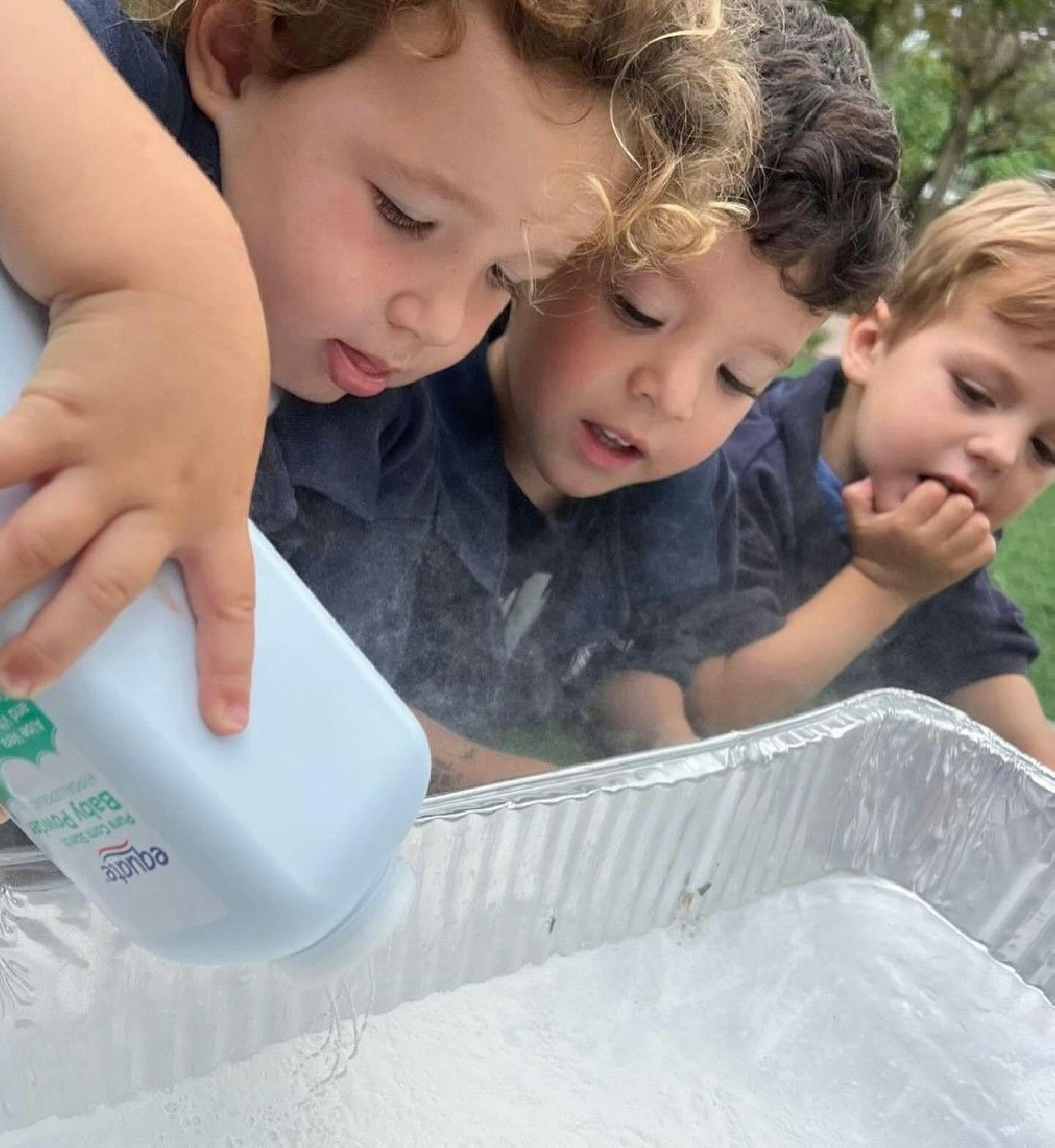 Three children looking at powder being poured into a tray