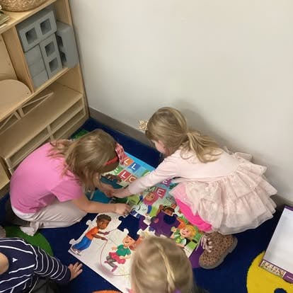 Children working together on a floor puzzle in a classroom