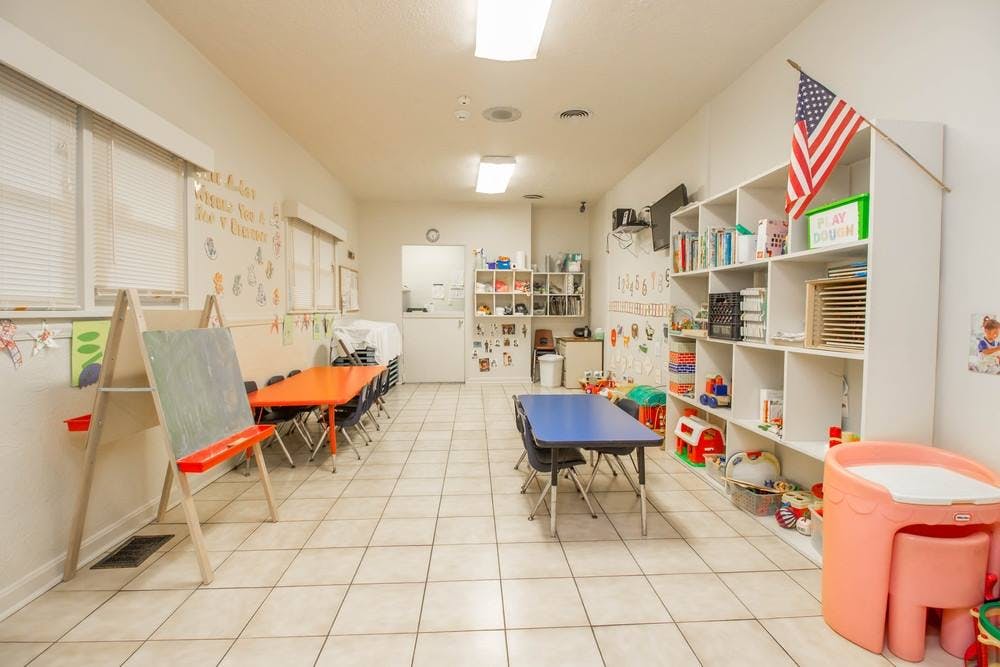 Classroom with tables, chairs, and shelves with an American flag