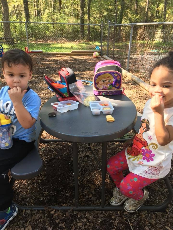 Two children eating at a small table outdoors