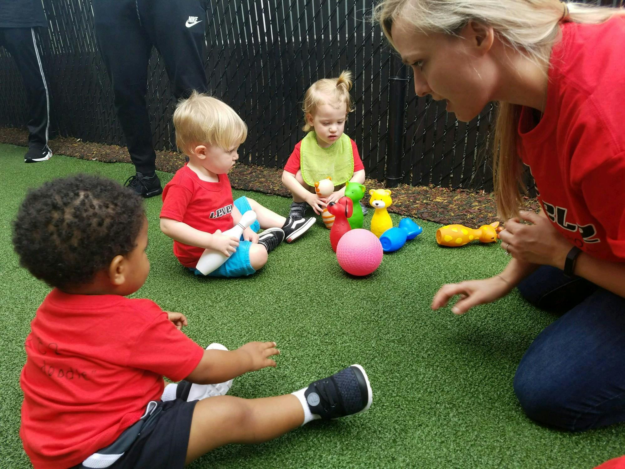 Adult and three children on grass with toys