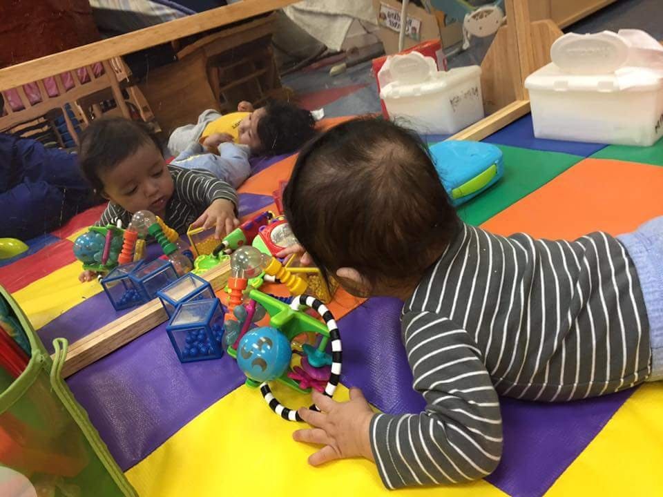 Two children playing with toys on a colorful mat
