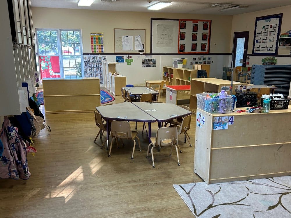 Empty classroom with small tables, chairs, and learning materials